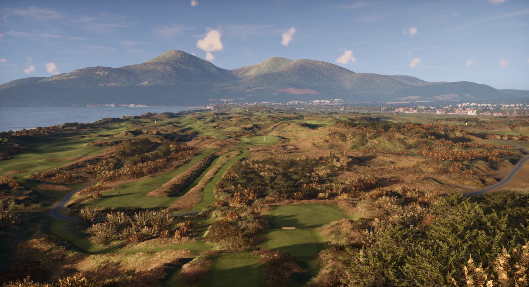A scenic view of a golf course with rolling hills, surrounded by lush greenery and distant mountains under a clear blue sky.