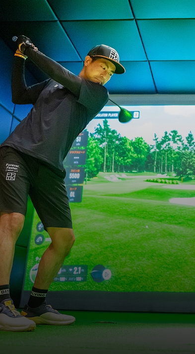 バーチャルコース画面付きインドアゴルフシミュレーターでスイングするゴルファー